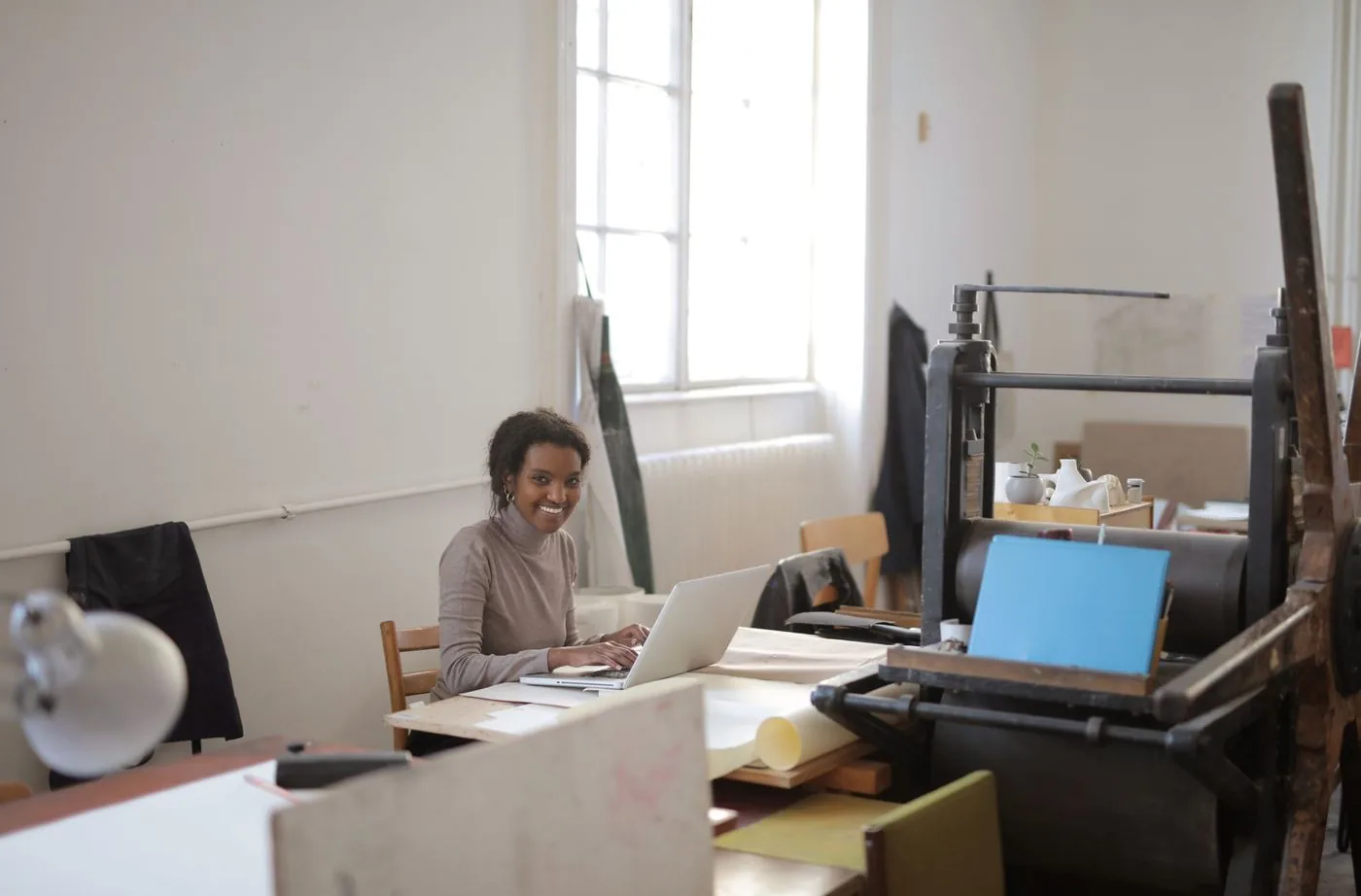 A woman working on a laptop in a bright studio